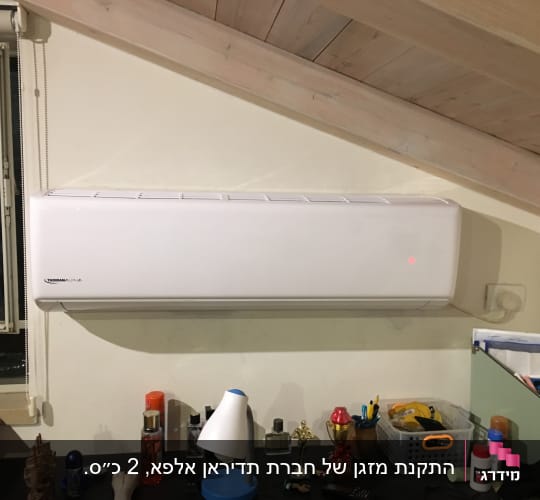 מזגן קיר לבן מותקן על קיר מתחת לתקרה